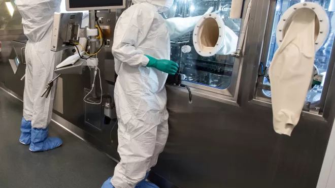 Two associates in full personal protective equipment stand at the production line